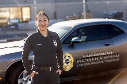 A police officer stands in front of a cruiser