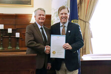 A gubernatorial proclamation is held by CWI President Gordon Jones and Idaho Governor Brad Little, both of whom are smiling.