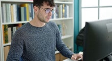 A student works at a PC in a college library.