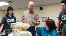 A professor teaches students about engineering using a model.