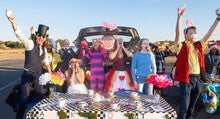 Students celebrate in front of their Halloween Trunk or Treat booth dressed as characters from Alice in Wonderland.