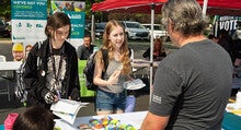 Two students accept materials from a campus club booth during the CWI Fall 2024 Resource Fair.