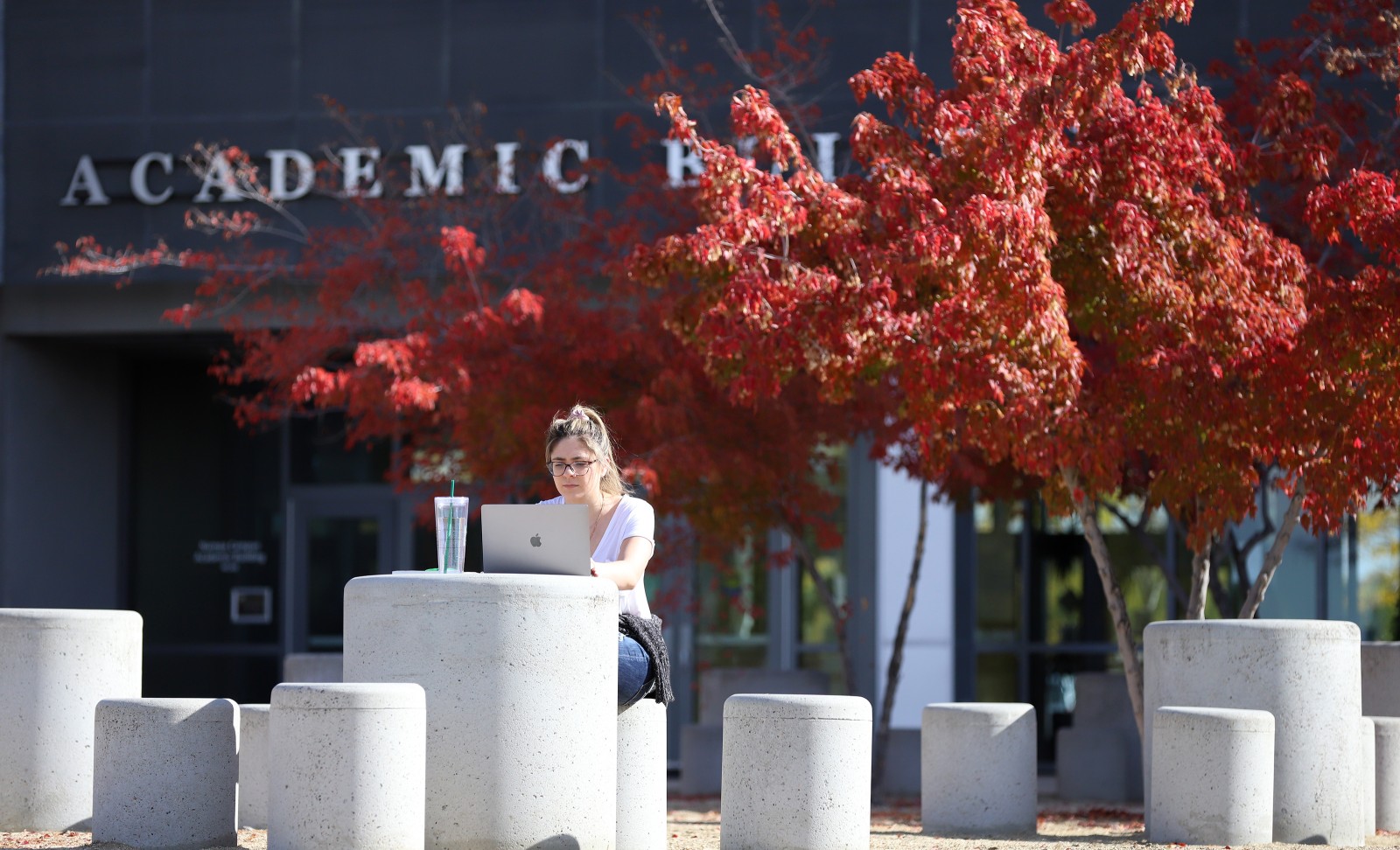 Student studying outside the Nampa Campus Academic Building in the fall