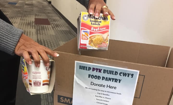 Individual placing canned food items in donation box. 