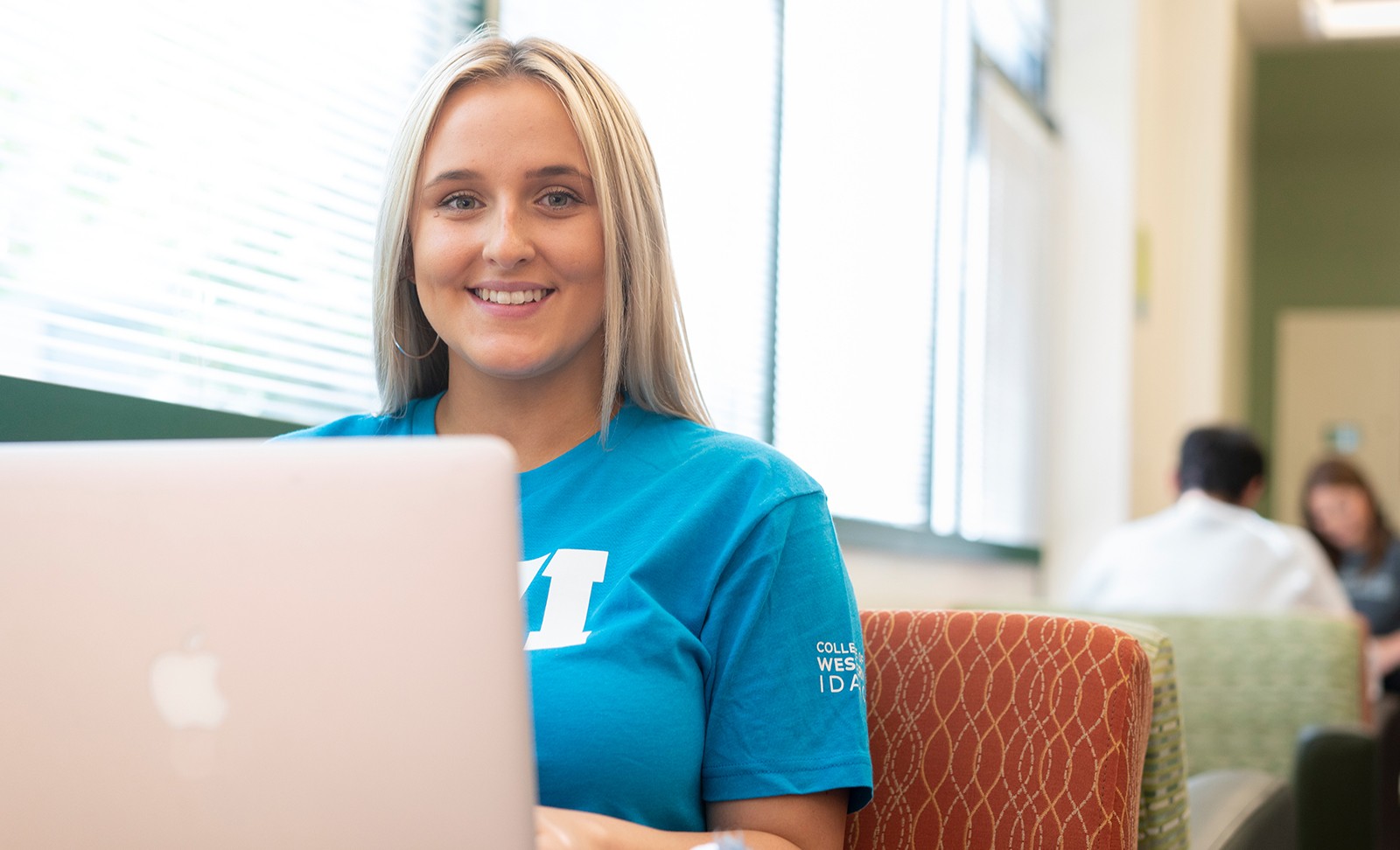 Student sitting at a laptop in common area on campus