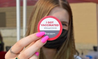 Woman holding up a sticker stating vaccination status