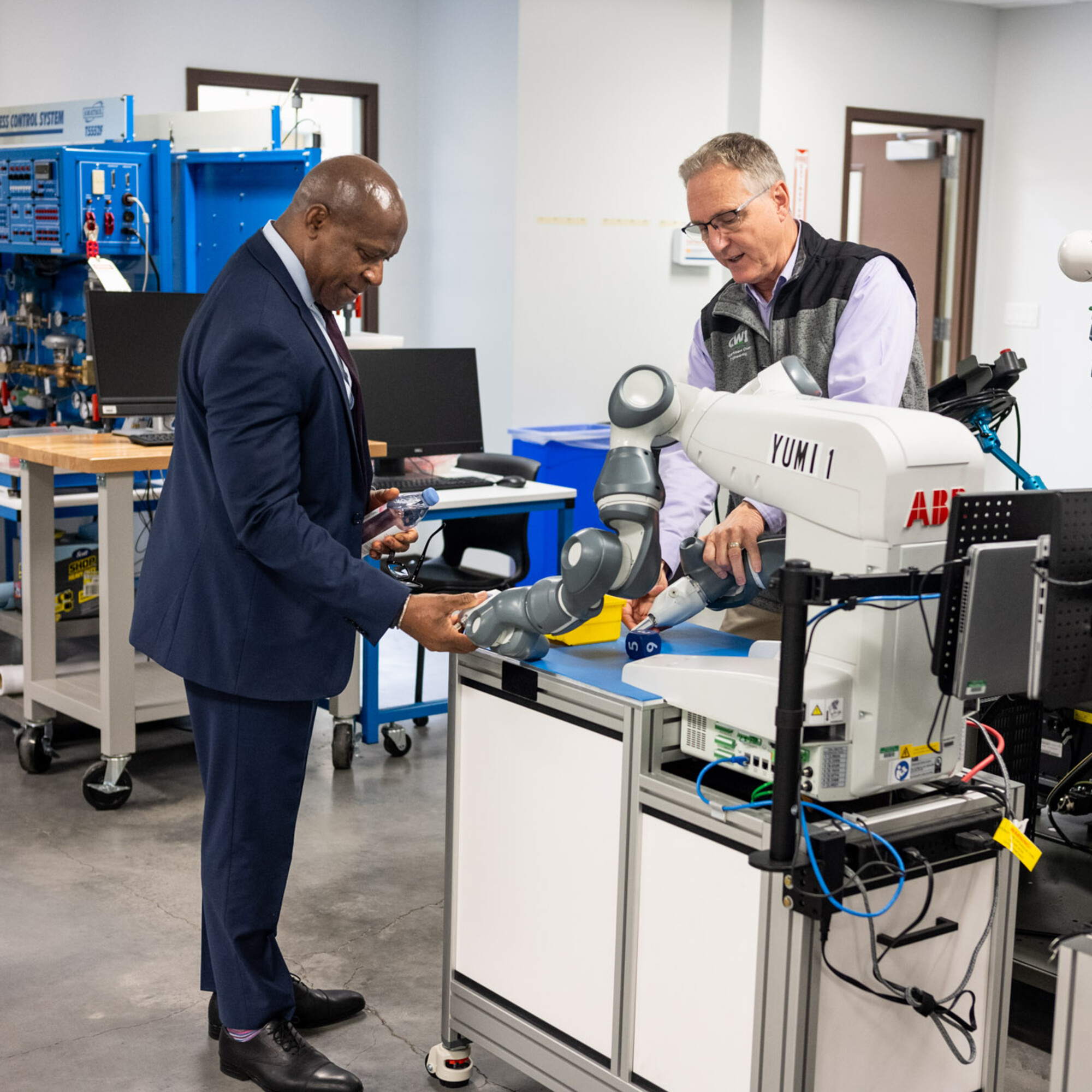 SUNY Oswego president Peter Nwosu inspects a robotic arm in the CWI Mechatronics Lab during a tour with Micron representatives.