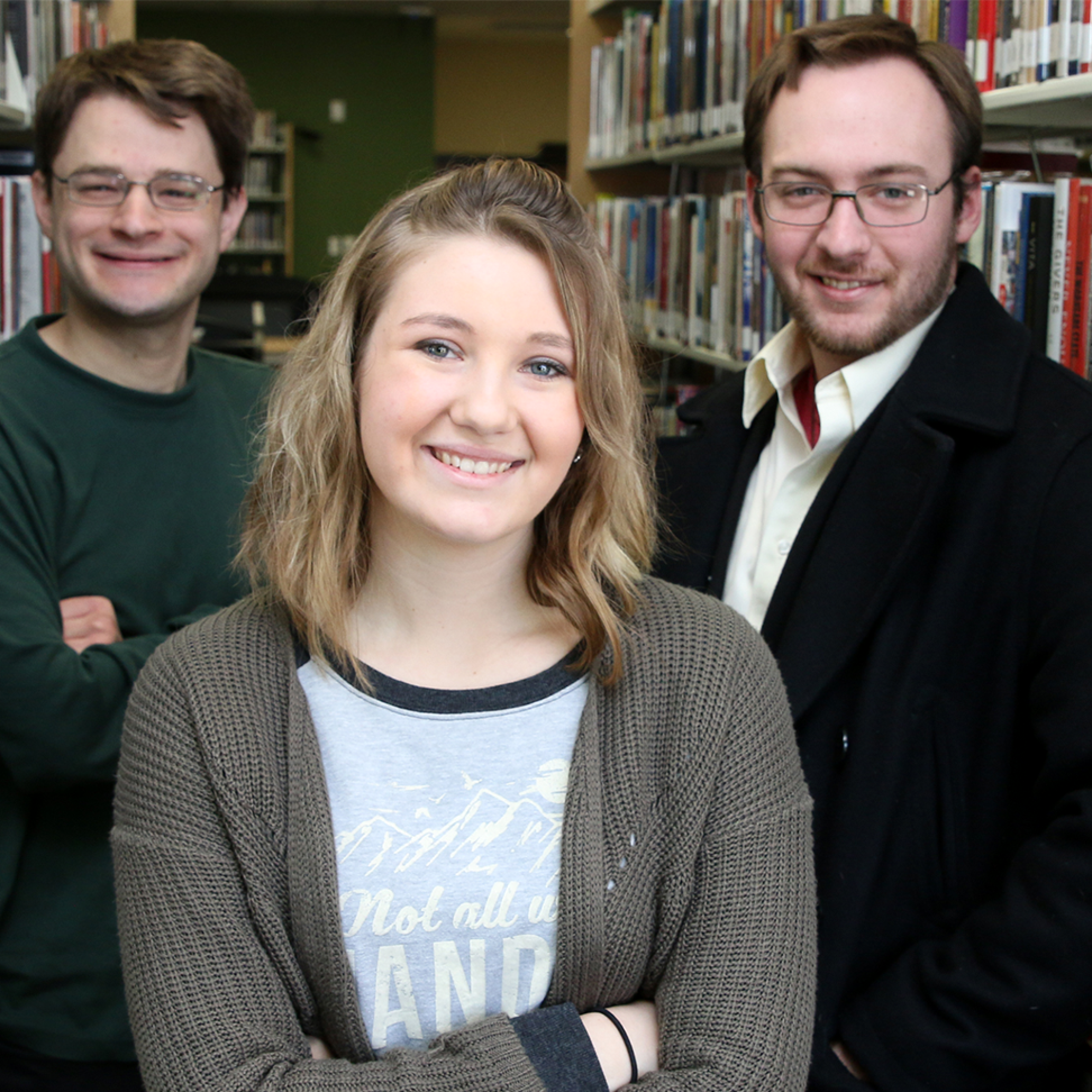 Three CWI students and participants in the Common Read Series event standing in the library. 