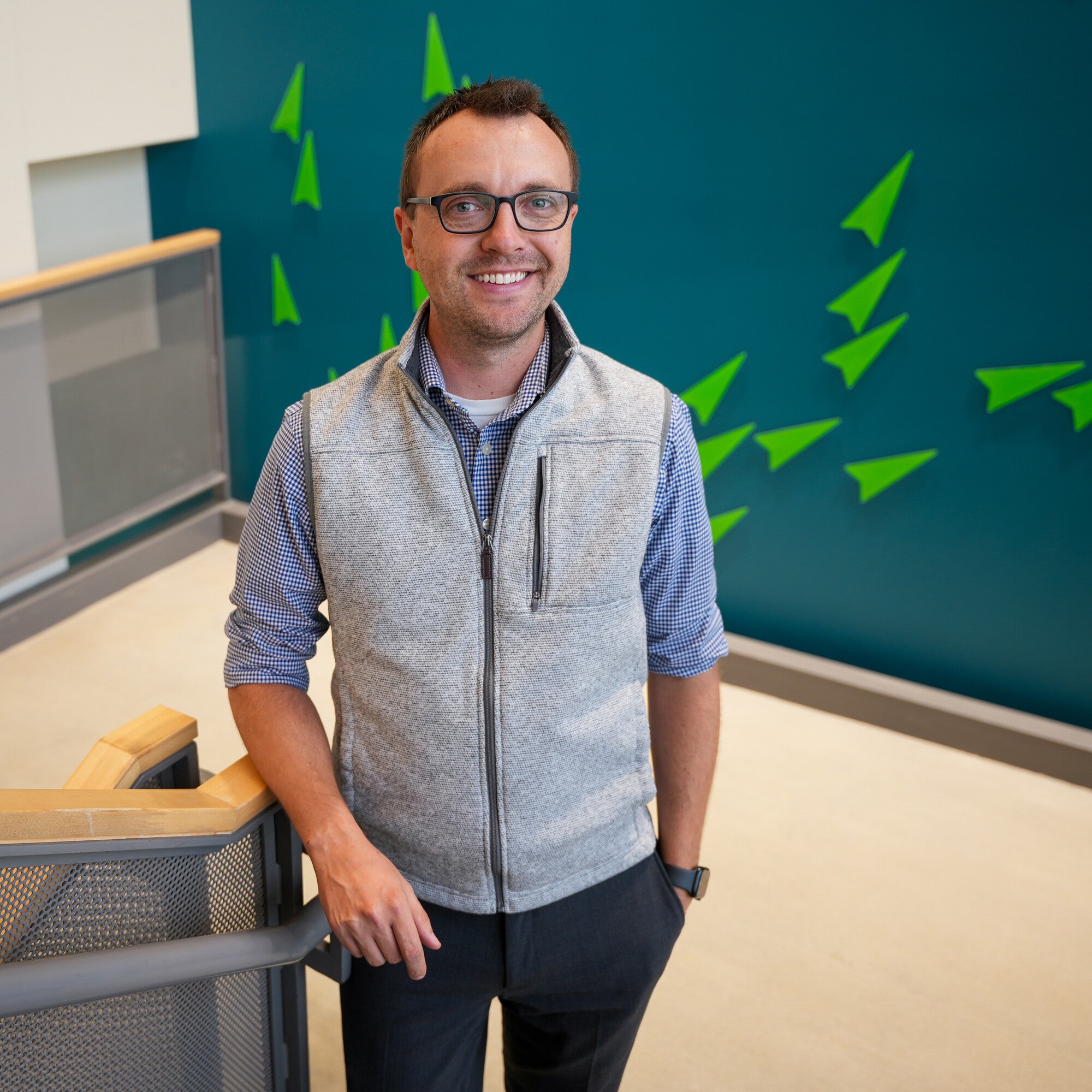Cody Phelps stands in front of backdrop and near stair railing