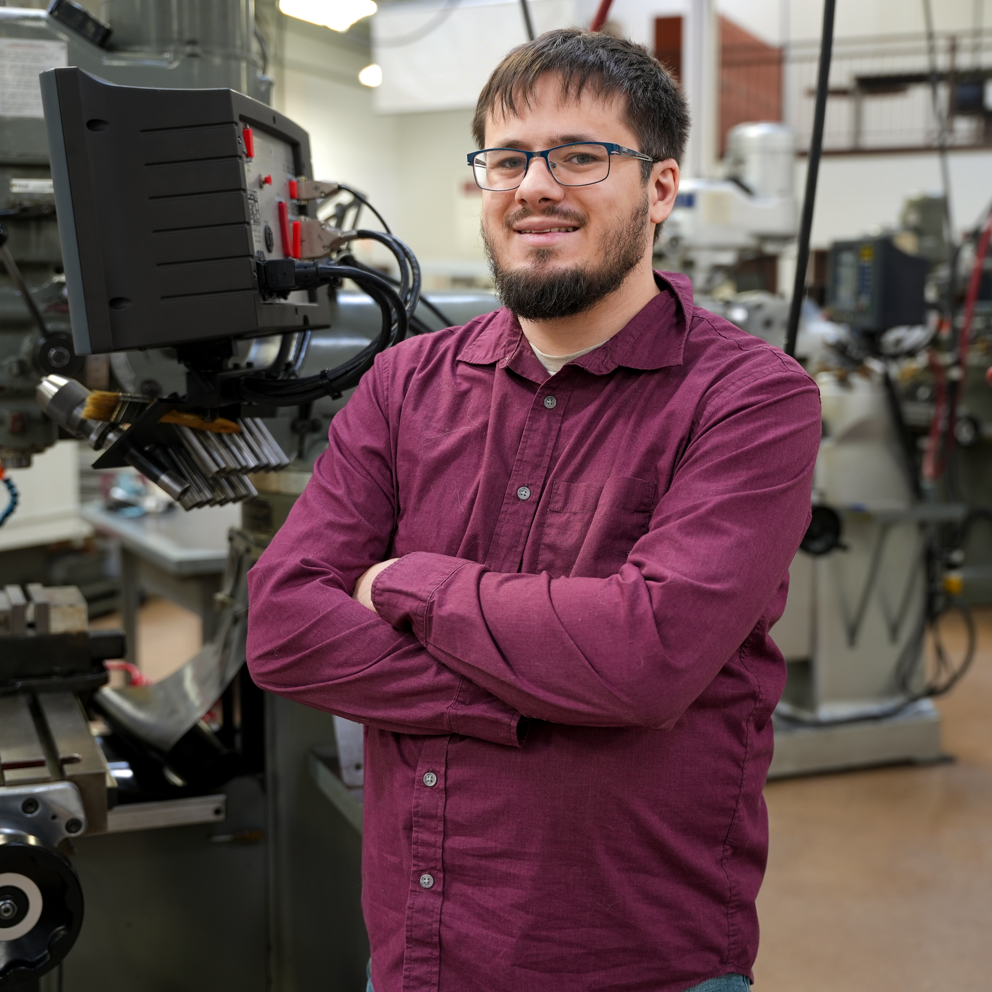 Student stands in front of machine tool technology equipment