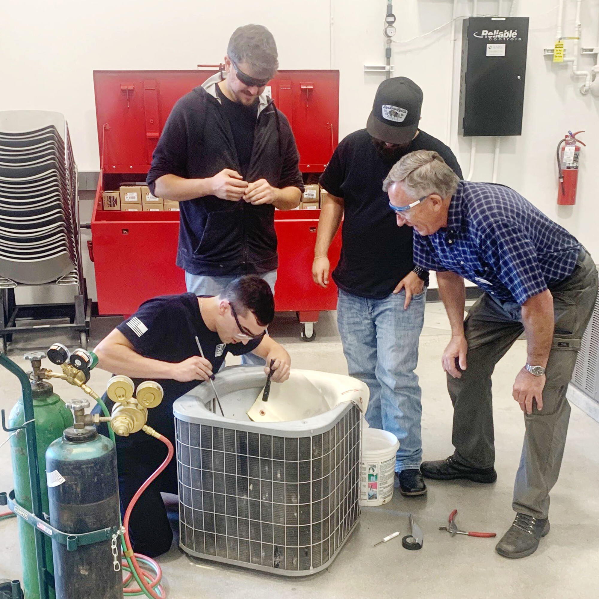 Students learn how to repair an air conditioning unit from an instructor.