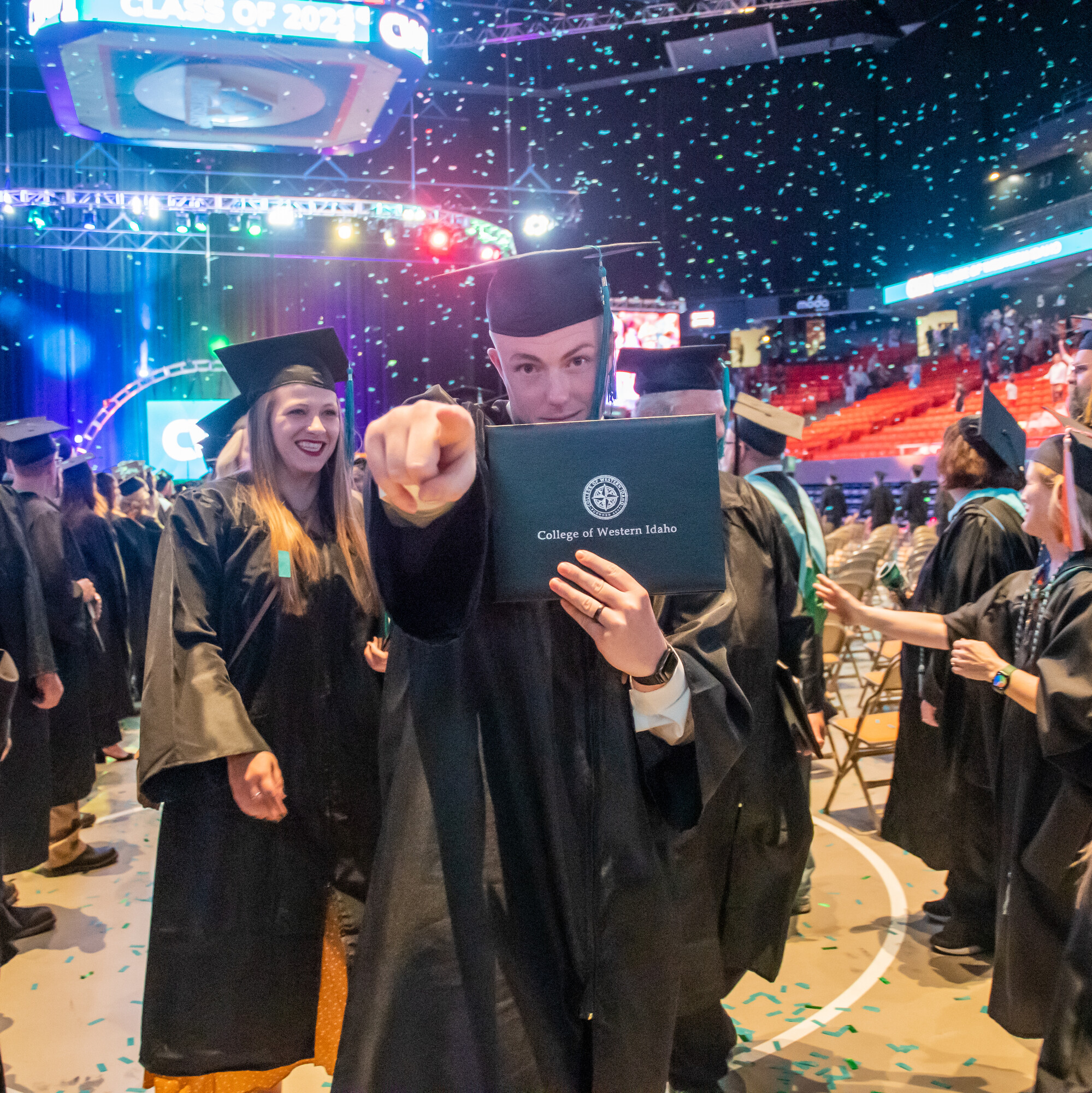 Graduate holding degree and pointing at camera