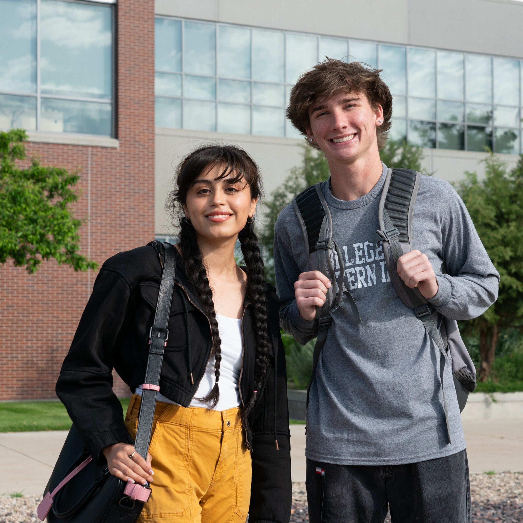 Two students with bags standing outside building