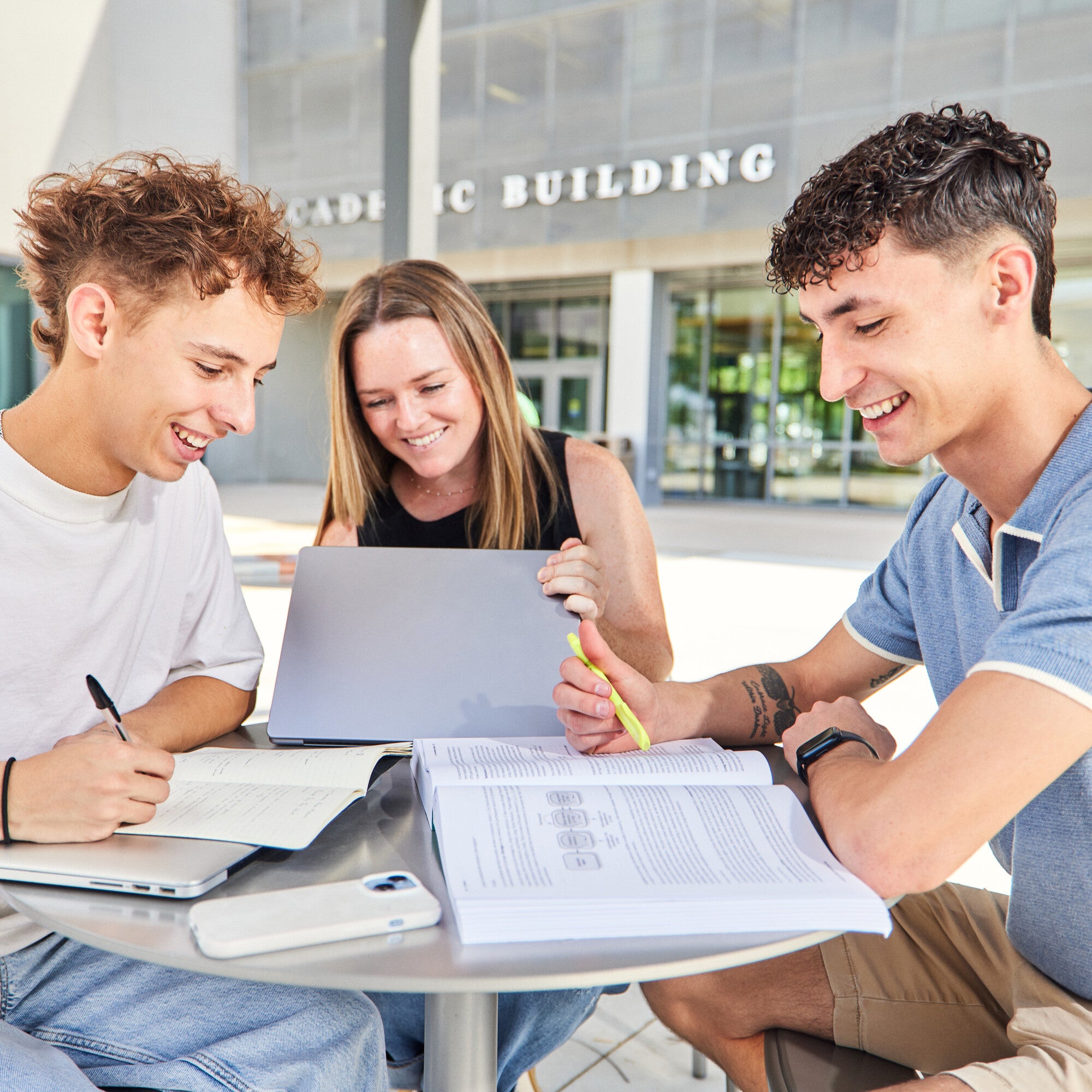 Three students working at a table with books
