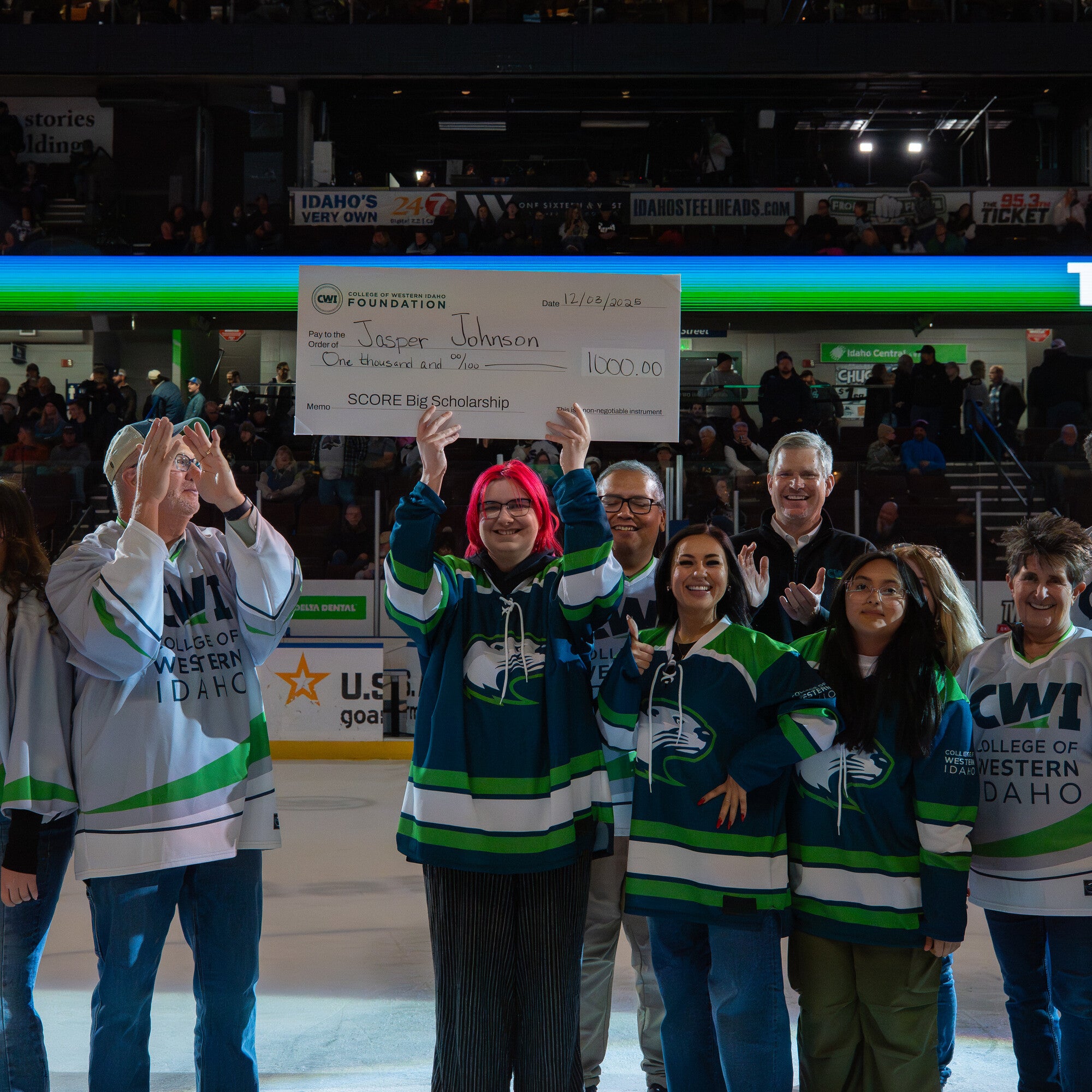 Person holding a large check stands in front of group people 
