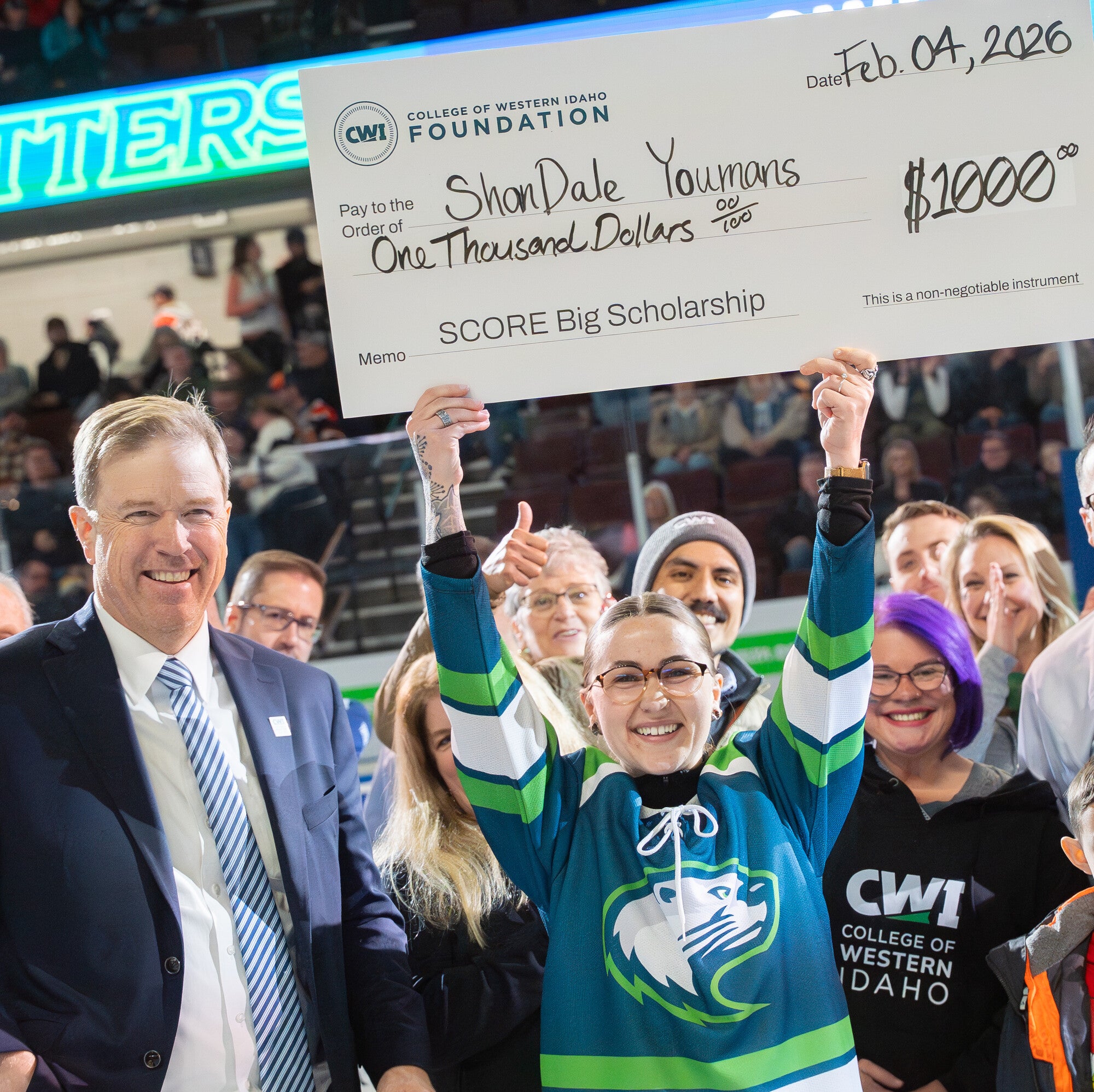 Student holding a large check in front of crowd