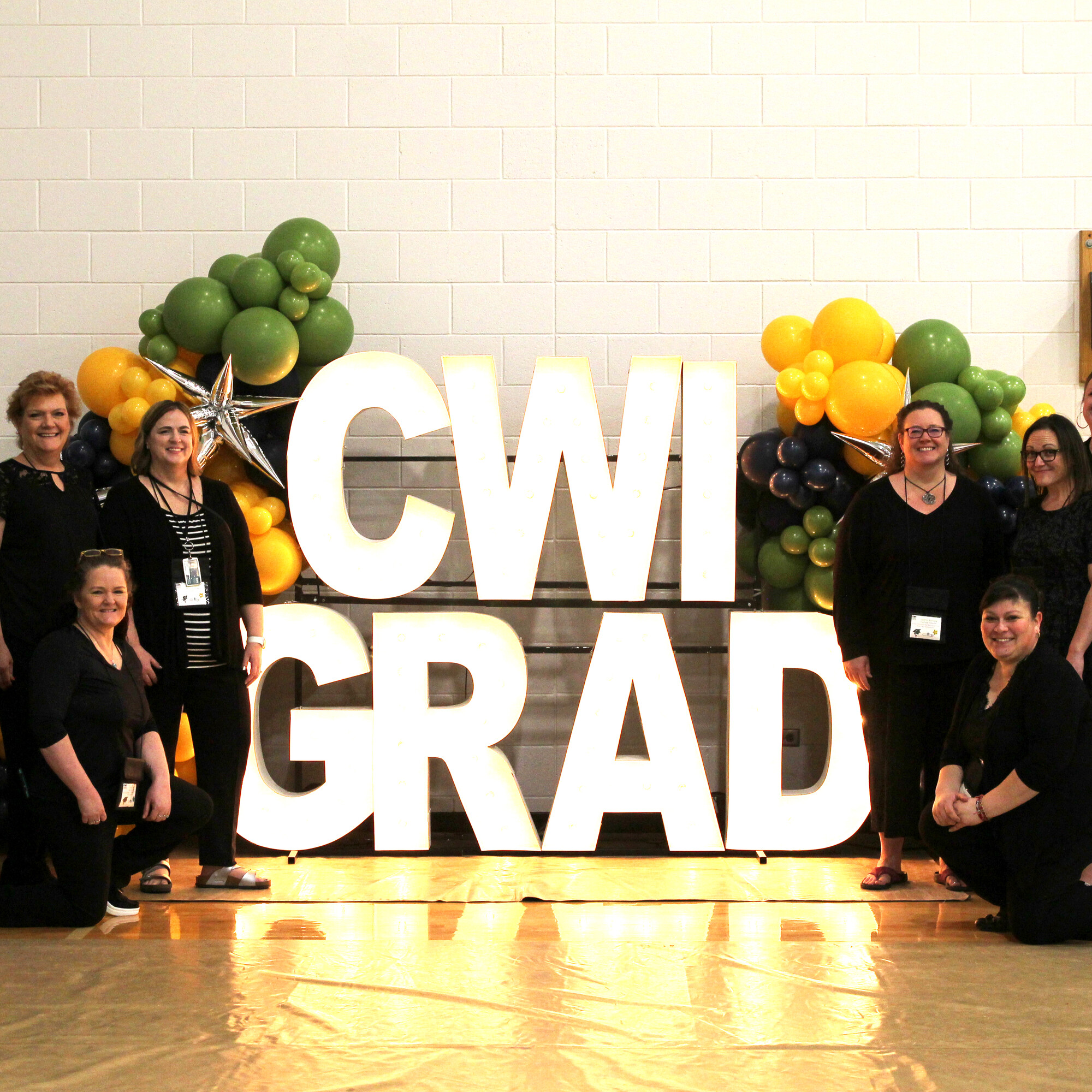 Employees standing in front of CWI Grad sign