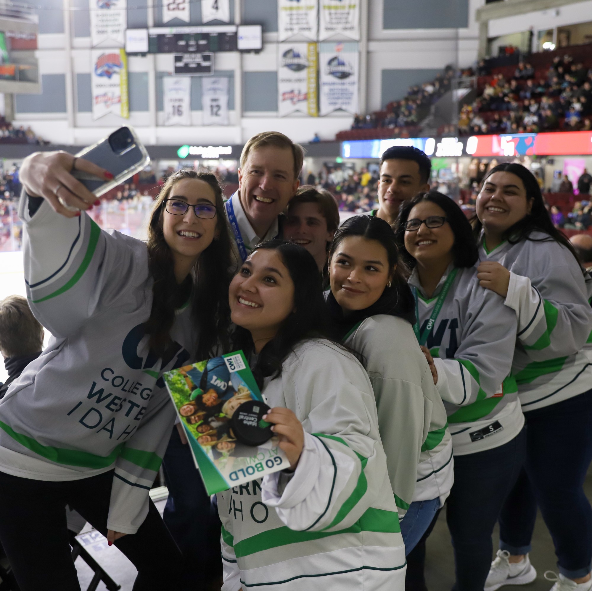 Students take a selfie with College president at a hockey game