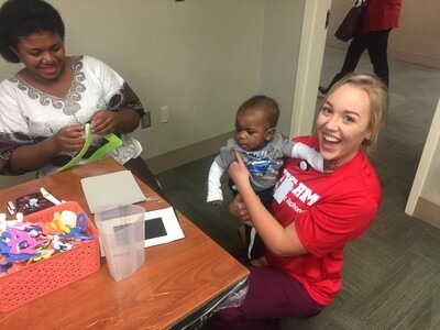Nursing student volunteering with mother and baby at St. Al's NICU