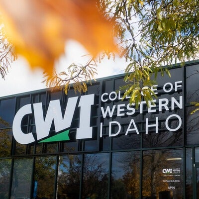 A photo of the CWI logo on a building, with Fall foliage.
