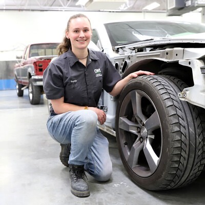 Sophie Rusling posing by a car in the Collision Repair Technology lab at CWI