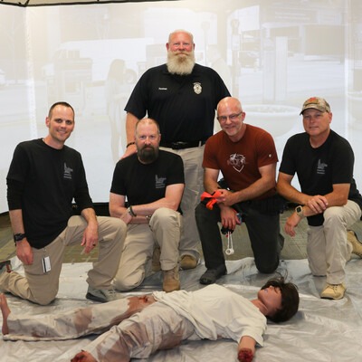 Medical tactical training posing with bleeding mannequin