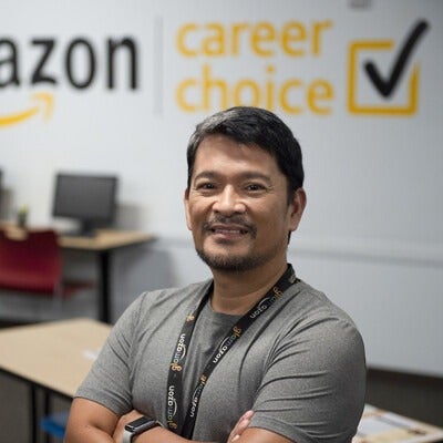 Individual standing a classroom with Amazon logo on the wall