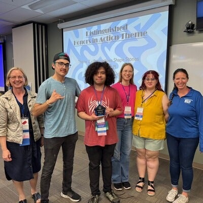 Students and faculty standing in front of projection screen