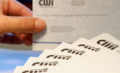 Person holding a CWI check next to a stack of CWI envelopes