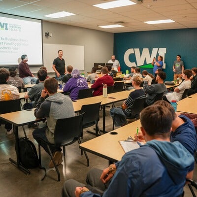 Students at desks with presenter in front of projection screen