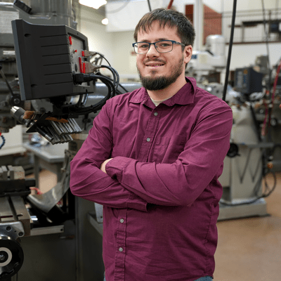 Student stands in front of machine tool technology equipment