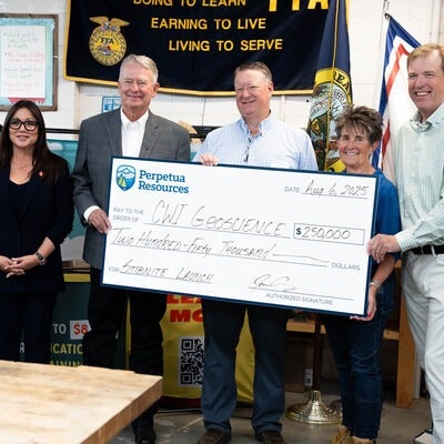 A group of people accept a ceremonial check donation for $250,000.