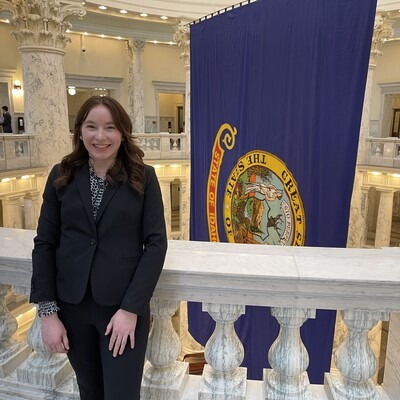 Flora Koenig in front of State of Idaho flag at Idaho State Capitol