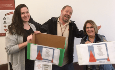 Employees holding Holiday Food Donation Drive boxes