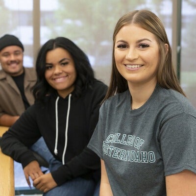 Three students sitting at computers in a classroom