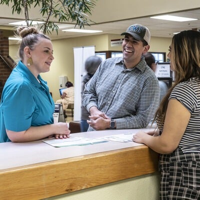 Three people chatting at a front desk