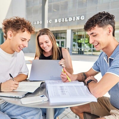 Three students working at a table with books