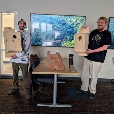 Two students hold American Kestrel nest boxes 