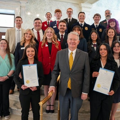 Group of people standing on staircase, with two people holding a proclamation