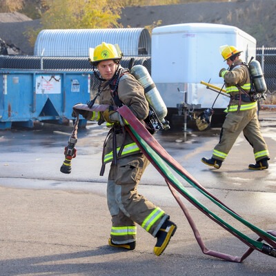 Fire student carrying hose