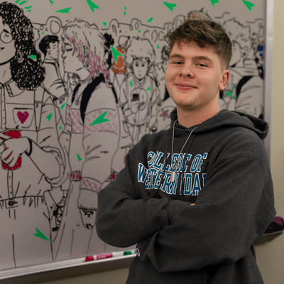 Caleb Chereji standing in front of his whiteboard mural