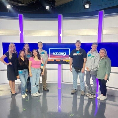Students touring a TV news station pose for a photo on set. 