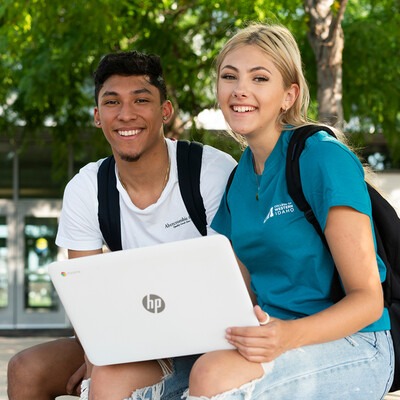 Students sitting outside Nampa Campus Academic Building with a laptop