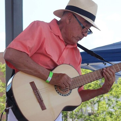 Guitarist and vocalist, Damian Rodriguez, playing a guitar outdoors