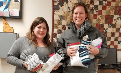 Two women holding sock donations. 