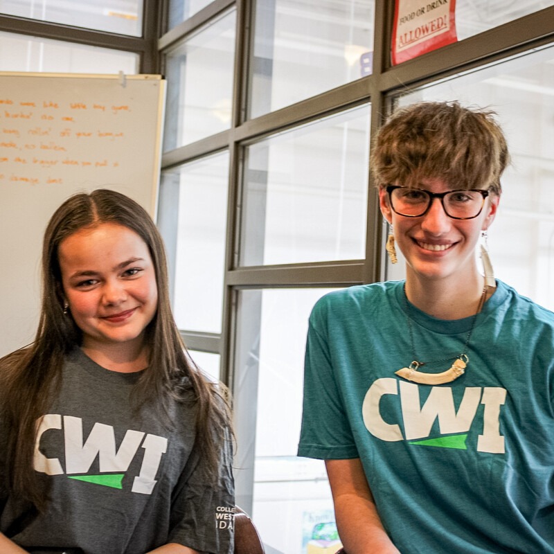 Two students wearing CWI t-shirts smile for a photo.