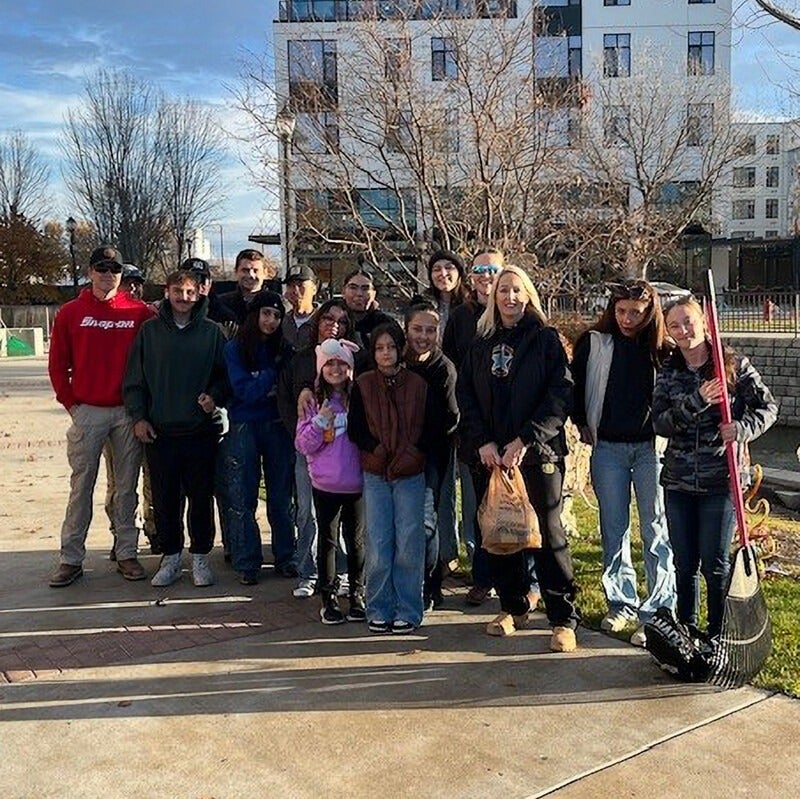 Group of people stand outside with rakes and lawncare equipment