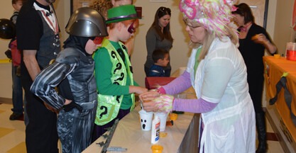 Students handing helping kids with Halloween craft