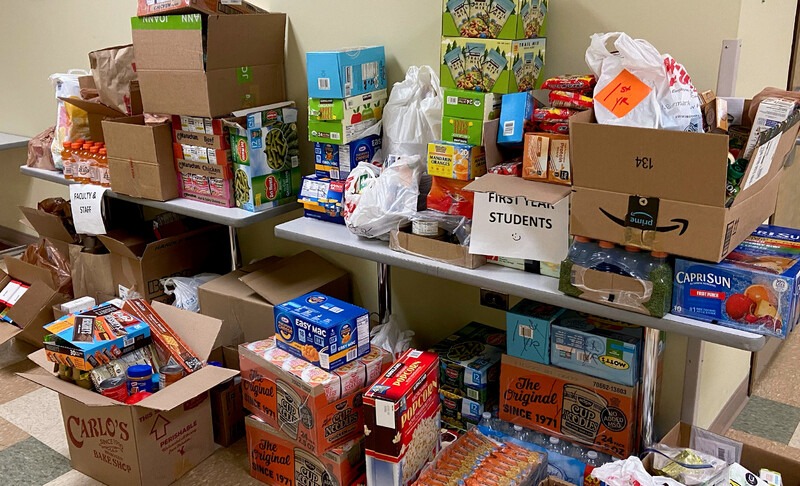 food pantry donations stacked on a table and on the floor