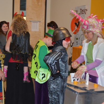 Students playing games with kids in costumes at the Halloween party.